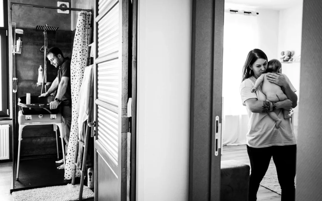 Maman portant son bébé vers la salle de bain où papa attends avec le bain portatif à Bruxelles